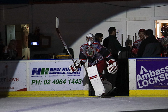 Newcastle Northstars goaltender, Charlie Smart, skates on to the ice from the players bench, the gate lit by a spotlight. Charlie is wearing the Northstars special Indigenous jersey.